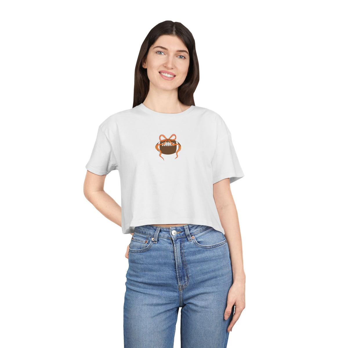 White crop tee worn by model, featuring football-and-bow graphic on chest