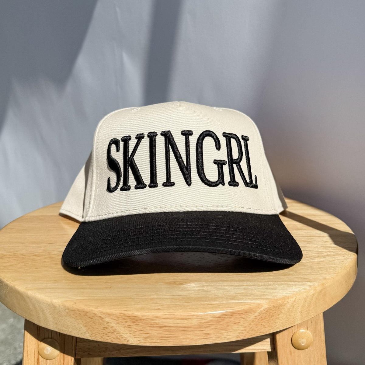 Cream trucker hat with black brim and embroidered SKINGRL logo