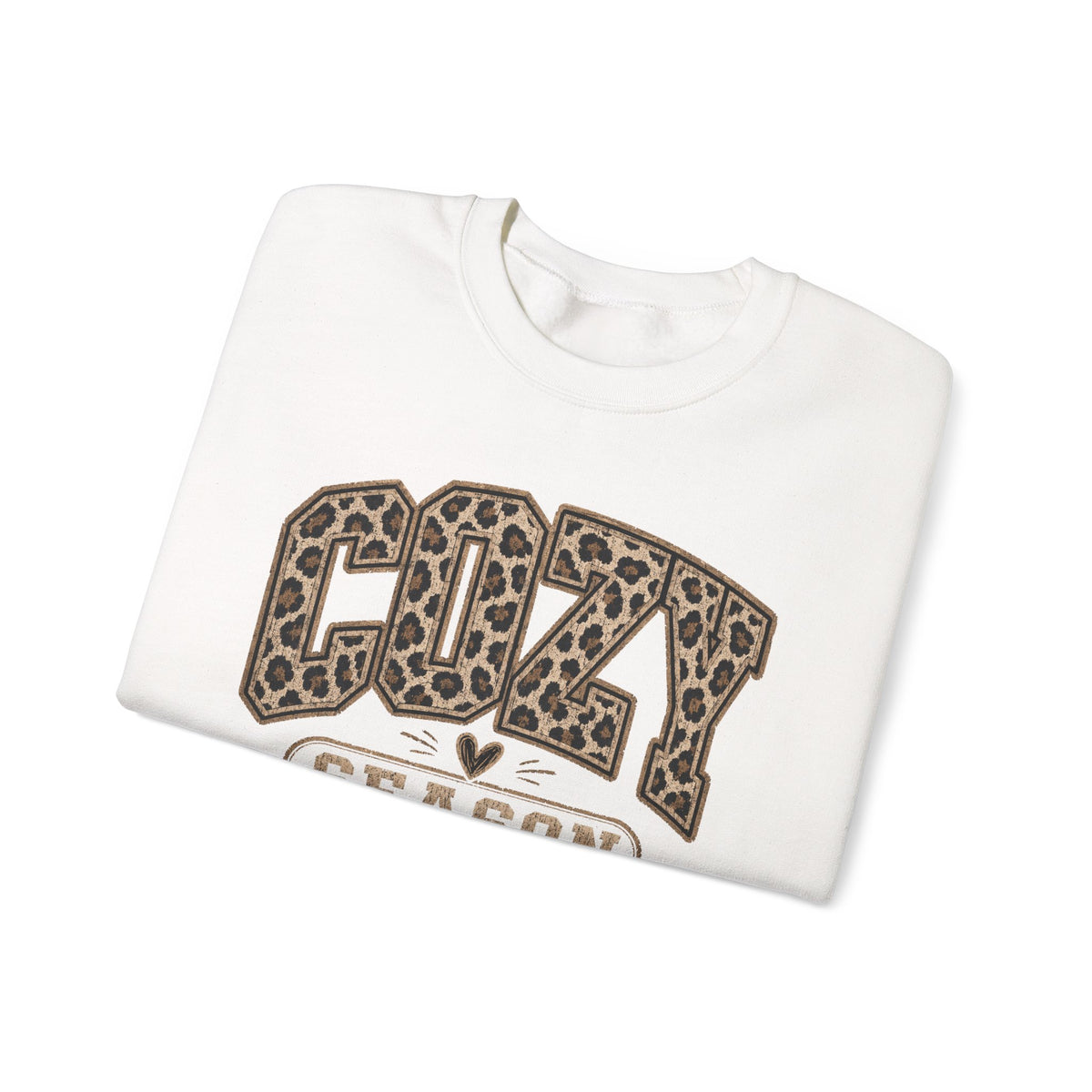 White crewneck sweatshirt folded, featuring leopard-print “COZY” front graphic