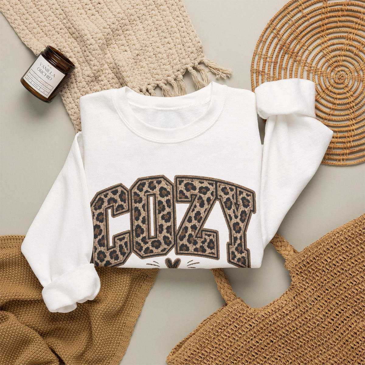 White crewneck sweatshirt front with leopard-print “COZY” and “SEASON” graphic