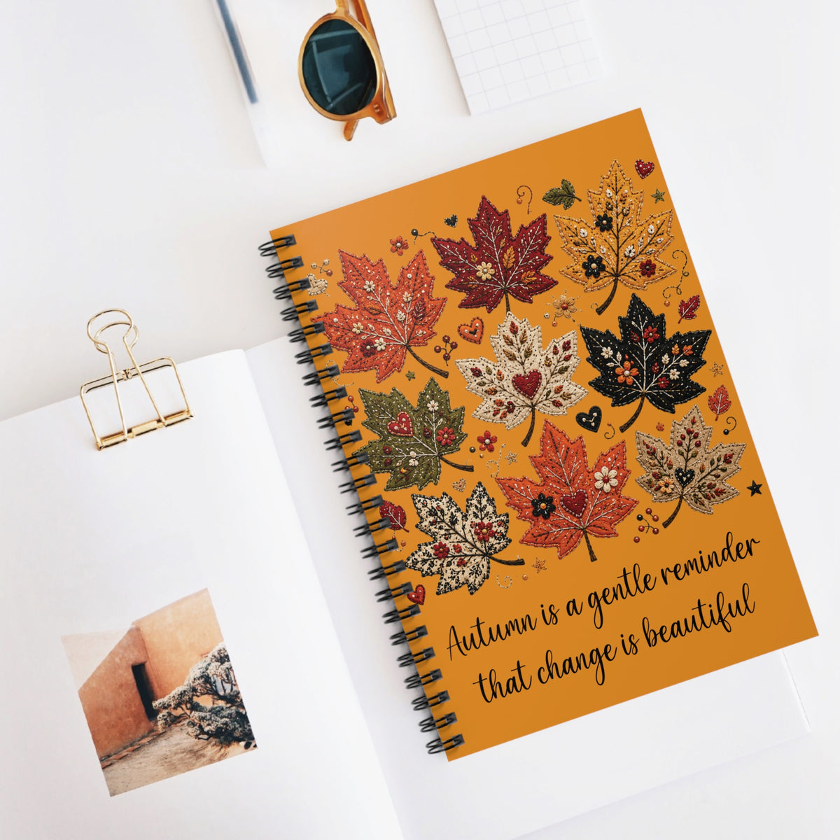 Orange autumn leaf spiral notebook on desk with quote cover and black spiral binding