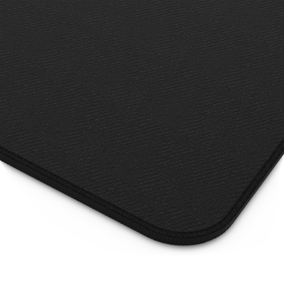 Textured dark desk mat corner with stitched border, no pattern visible