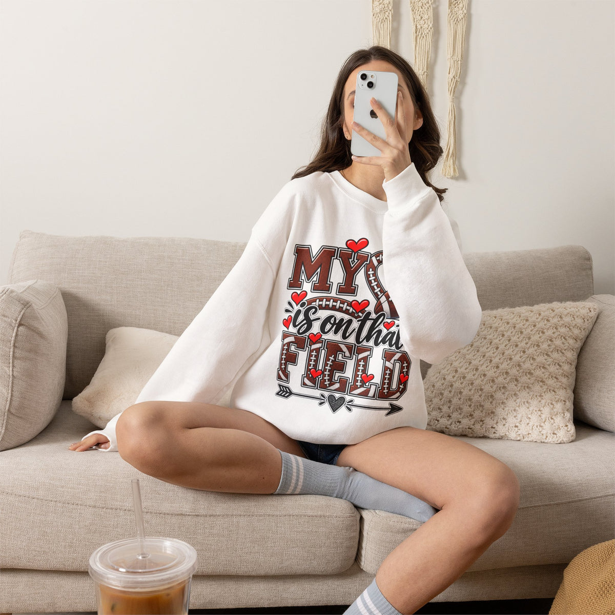White crewneck sweatshirt on model with 'My' heart and football graphic