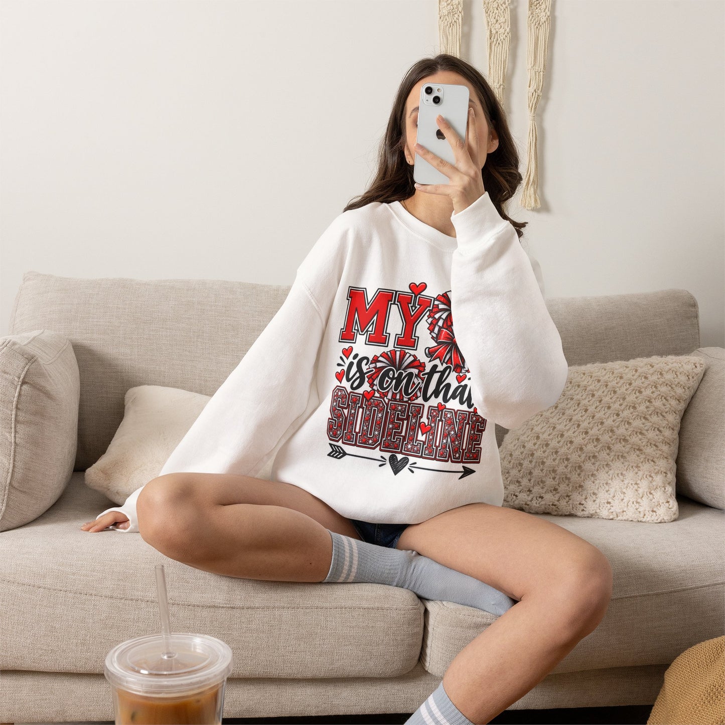 White crewneck sweatshirt on model with red heart sideline graphic, long sleeves