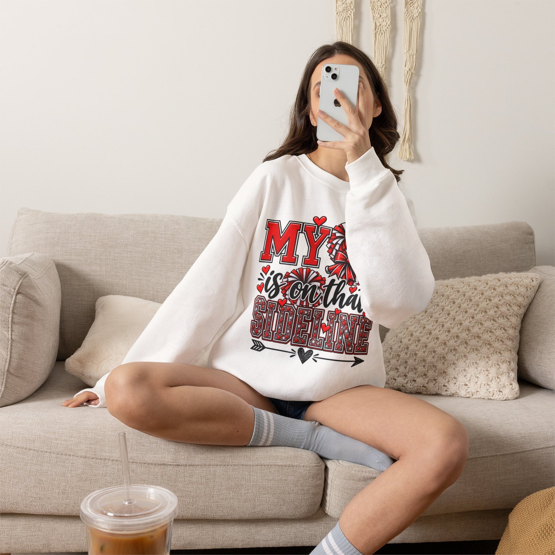 White crewneck sweatshirt on model with red heart sideline graphic, long sleeves