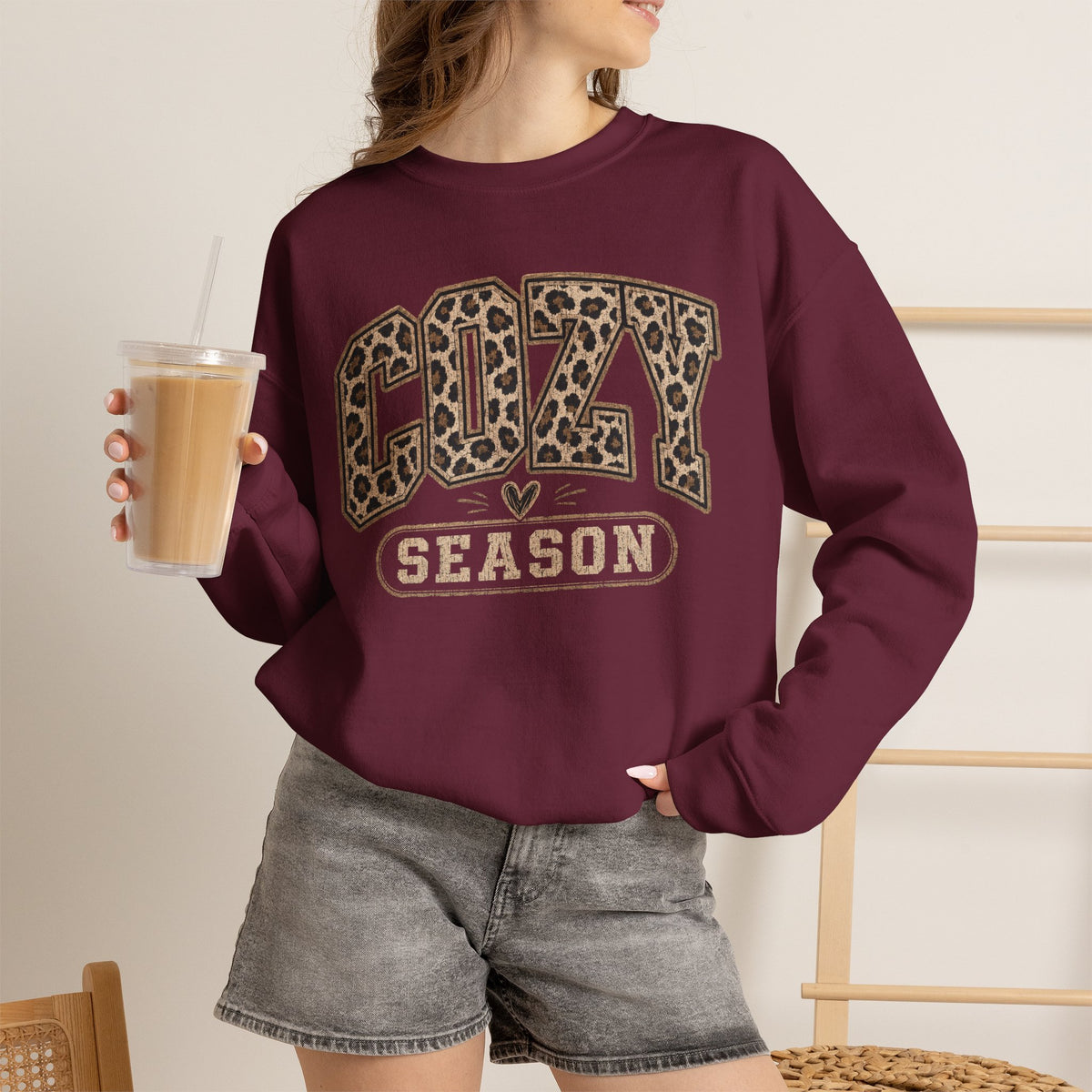 Maroon crewneck sweatshirt with leopard-print “COZY SEASON” graphic on chest