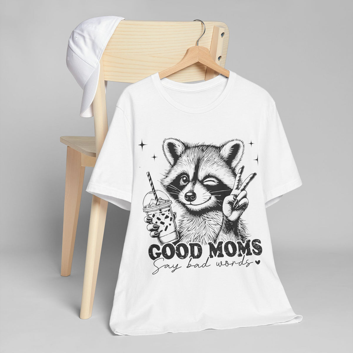 White unisex jersey T-shirt on hanger with raccoon peace sign and Good Moms graphic
