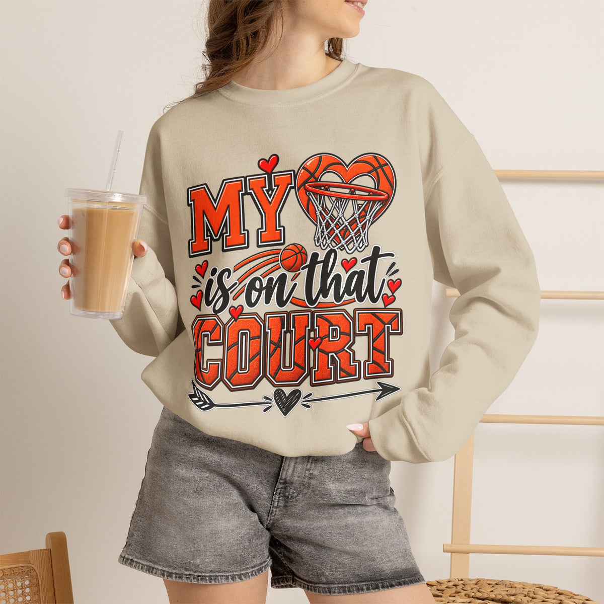 Sand crewneck sweatshirt with basketball heart graphic, worn with denim shorts