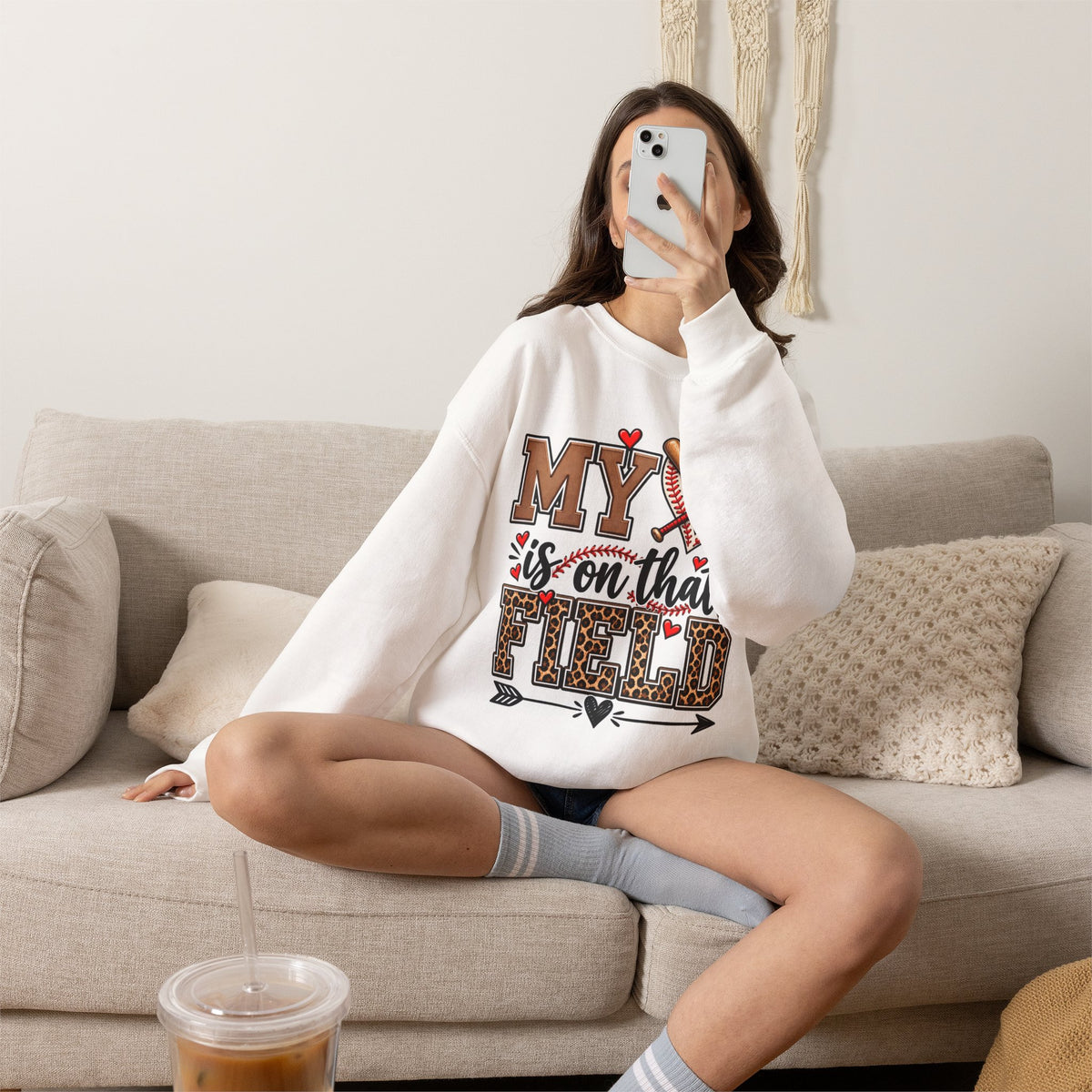 White crewneck sweatshirt with baseball heart and crossed bats front graphic, worn