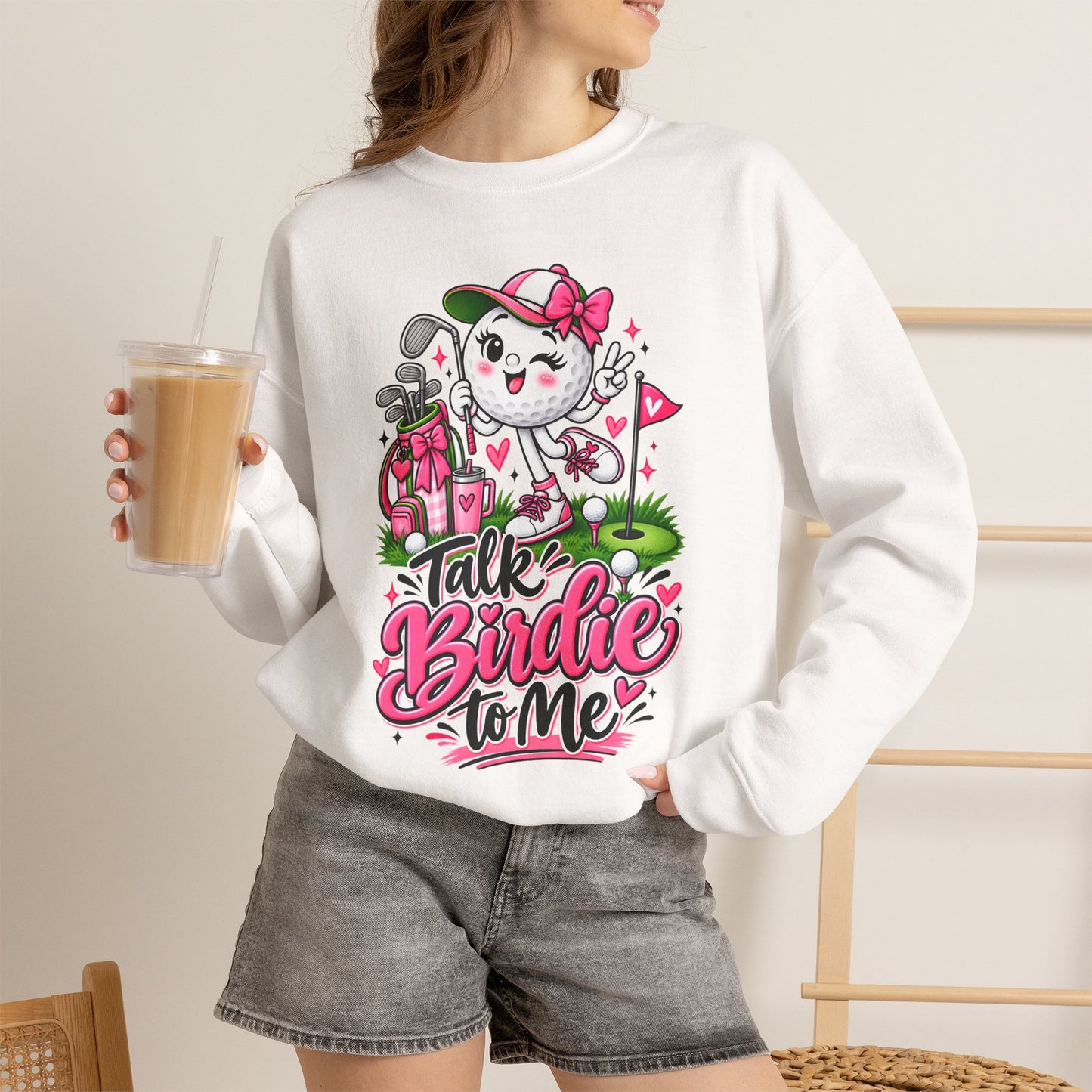 White crewneck sweatshirt on model with golf cat character graphic and pink floral hearts
