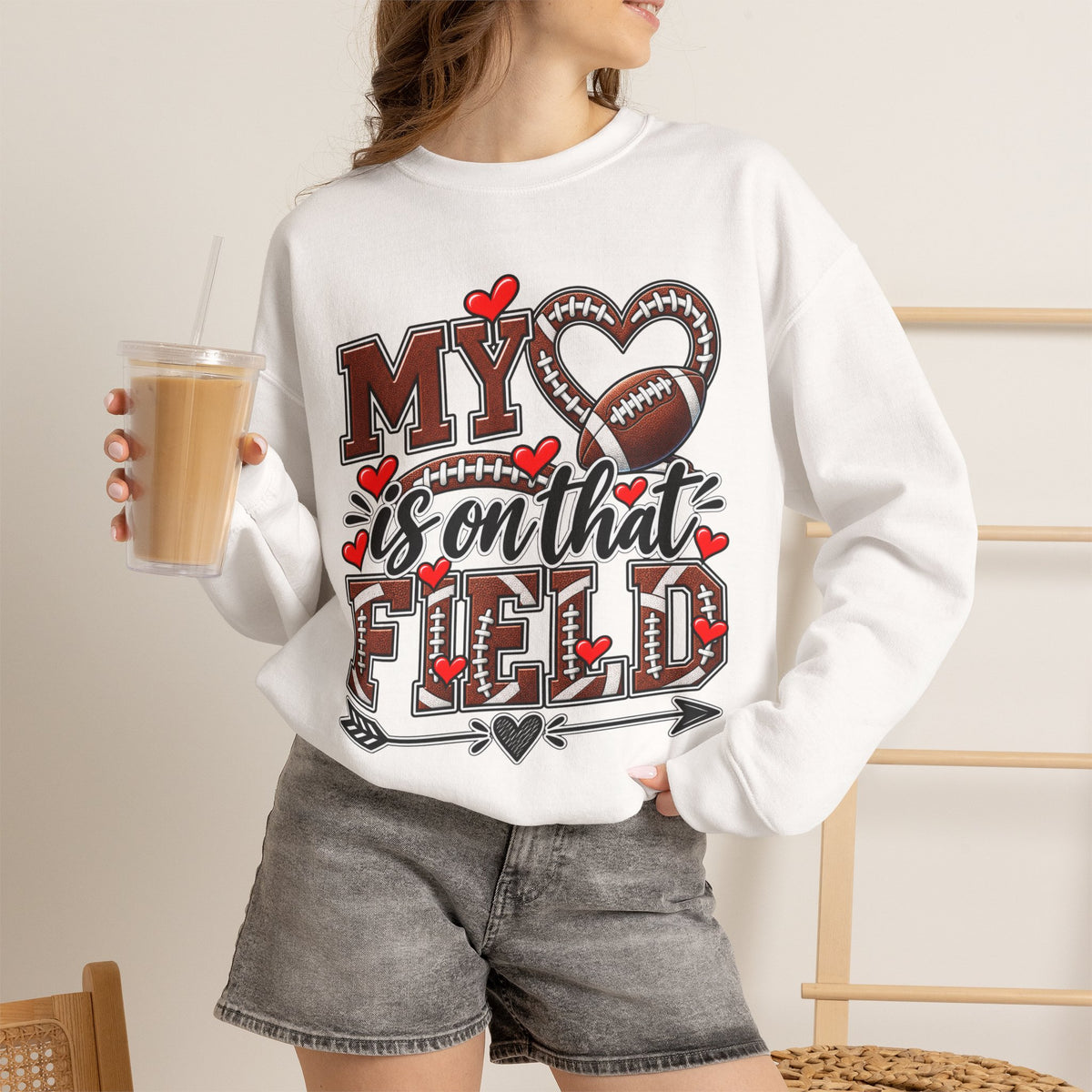 White crewneck sweatshirt on model with 'My' heart and football graphic