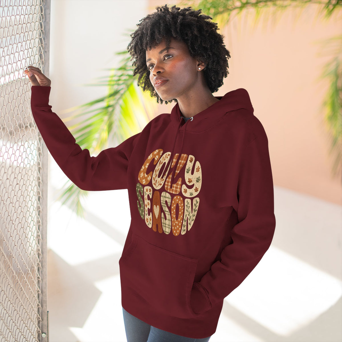 Burgundy fleece hoodie on model with drawstring hood, front pocket, and “Cozy Season” graphic