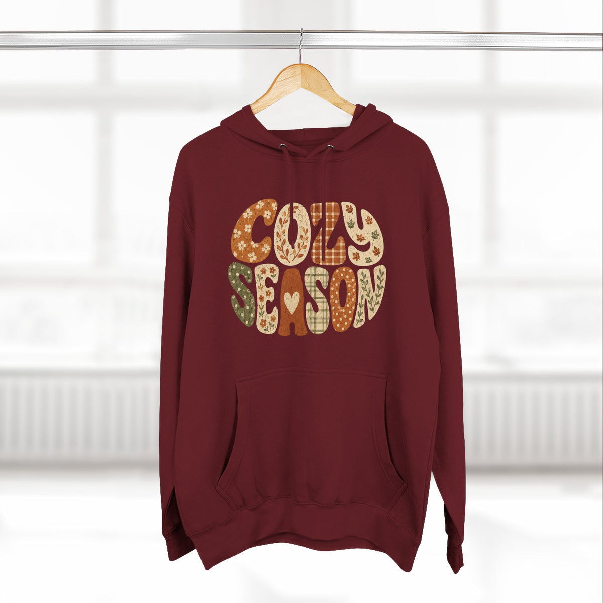 Burgundy fleece hoodie with drawstring hood, front pocket, and “Cozy Season” graphic