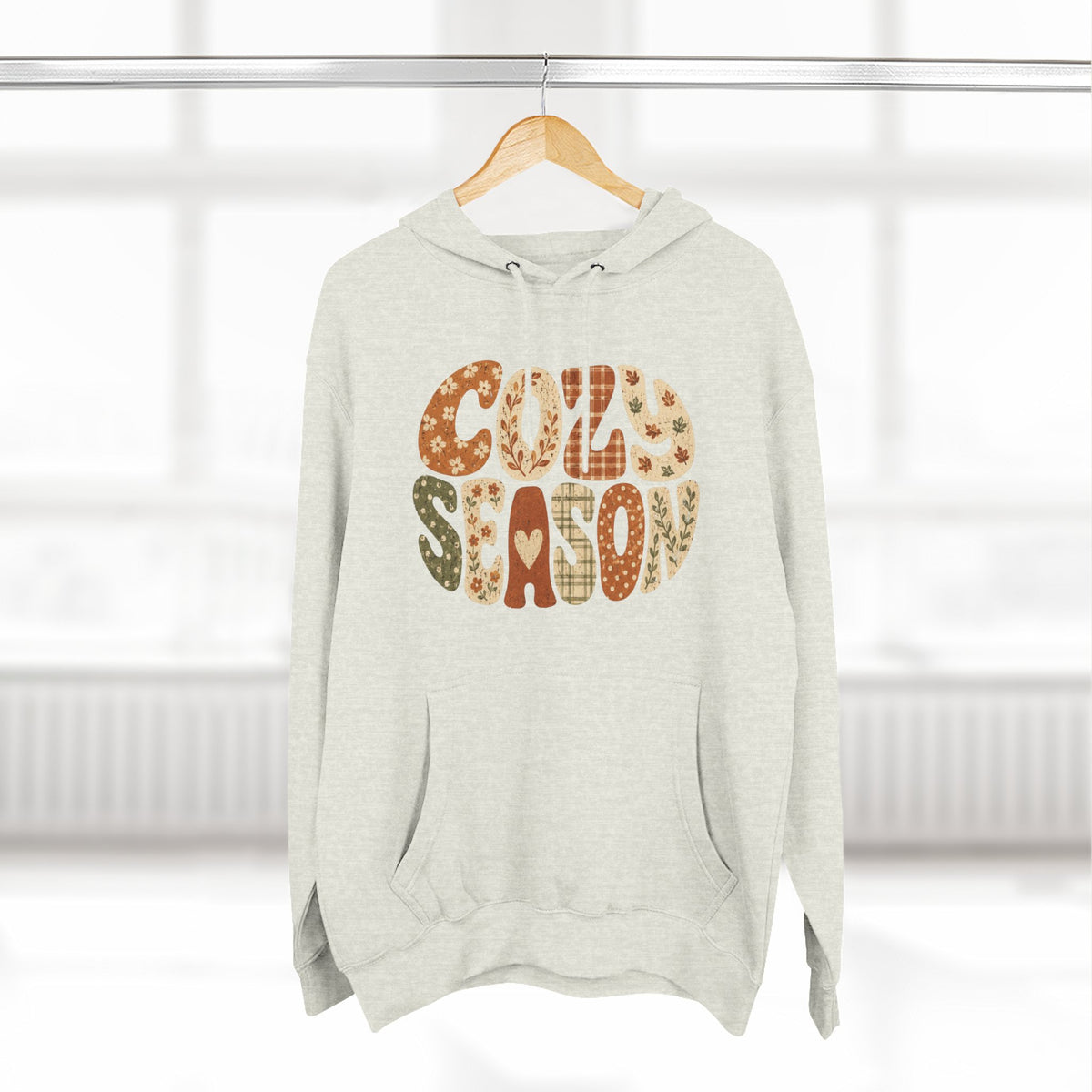 Oatmeal heather fleece hoodie with drawstring hood and front pocket; “Cozy Season” graphic