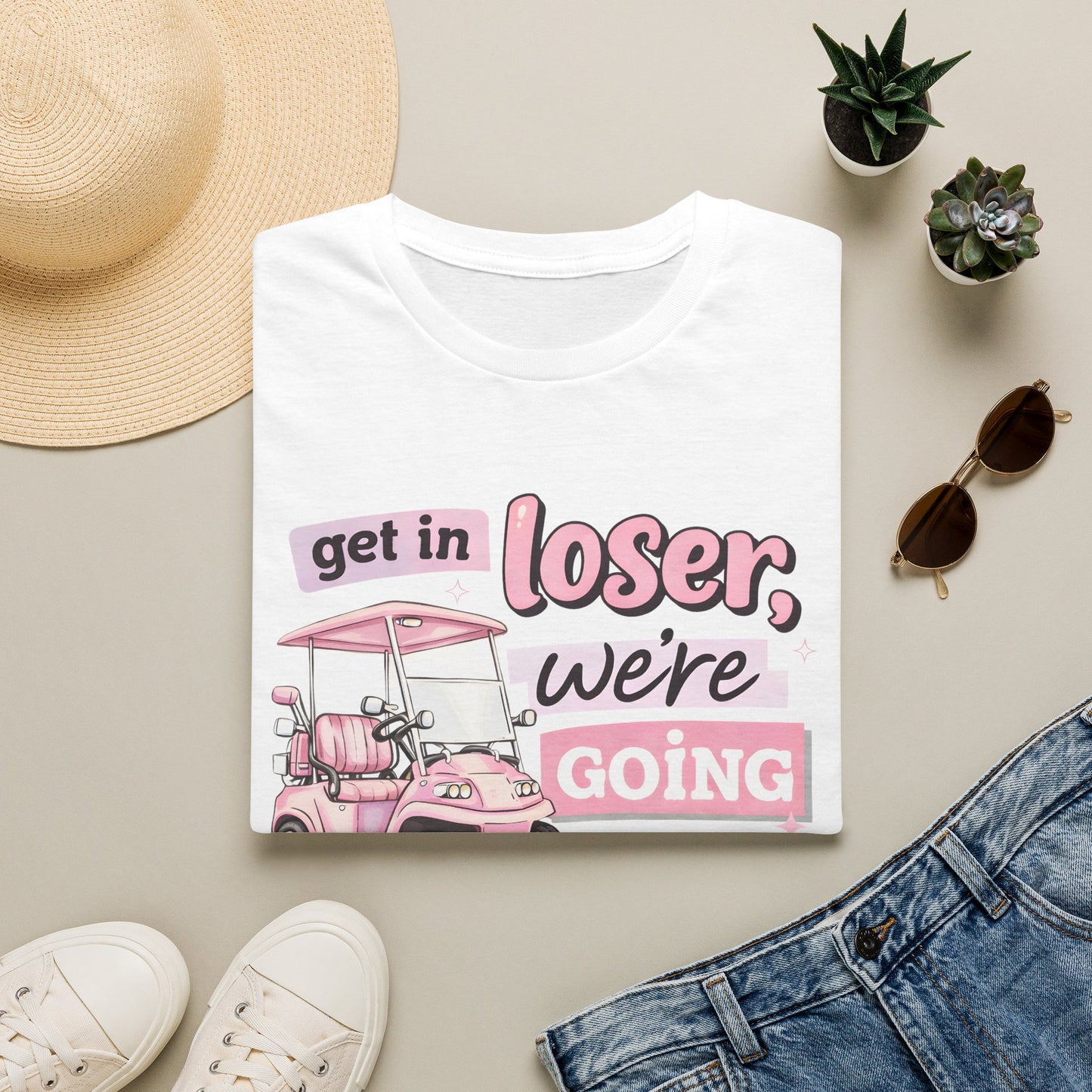 White golfing graphic T-shirt with pink cart illustration and “we’re going golfing”