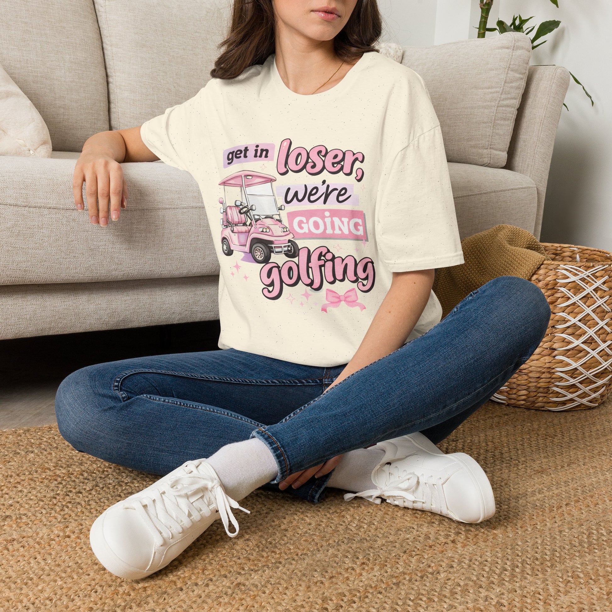 Cream T-shirt worn on model with pink “Get in Loser” golf cart graphic