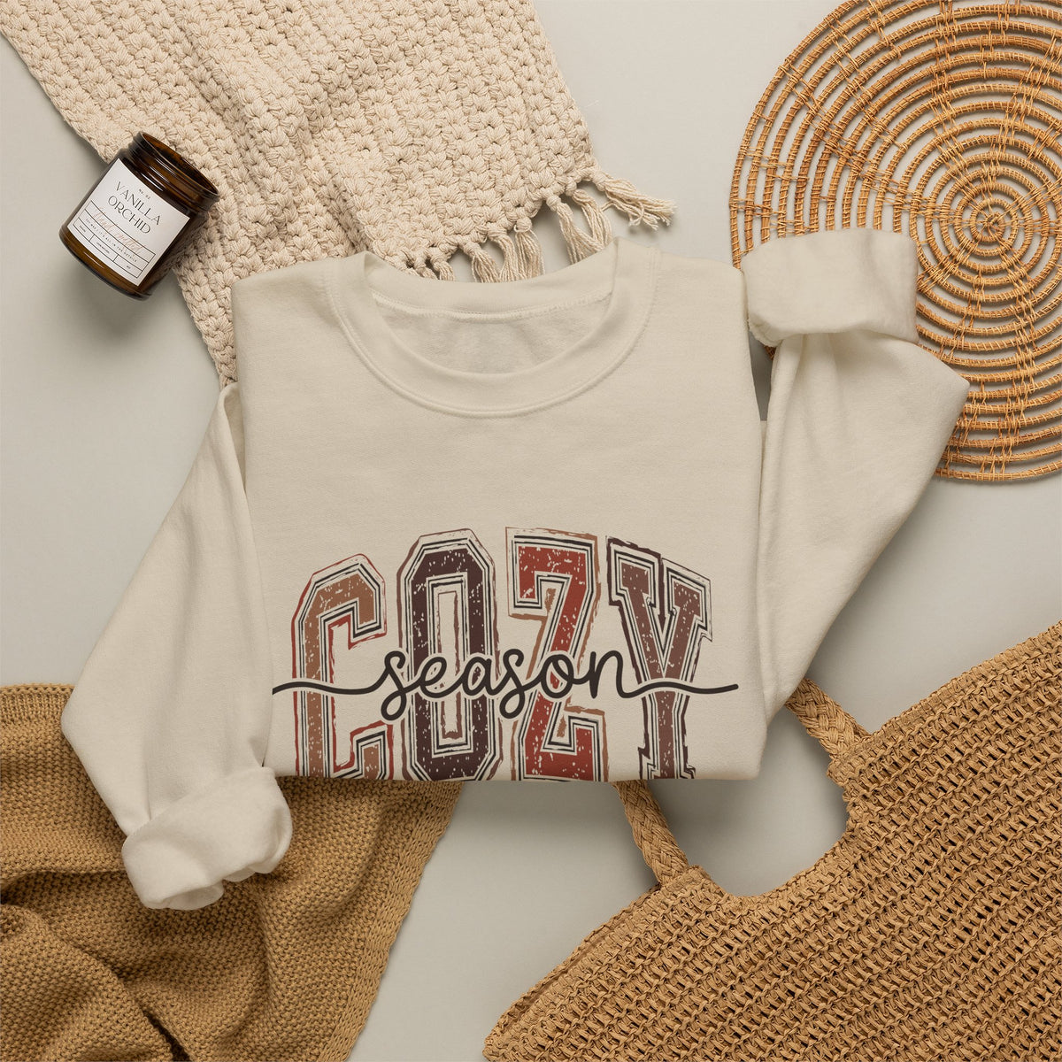 White crewneck sweatshirt with Cozy Season front graphic, sleeves visible