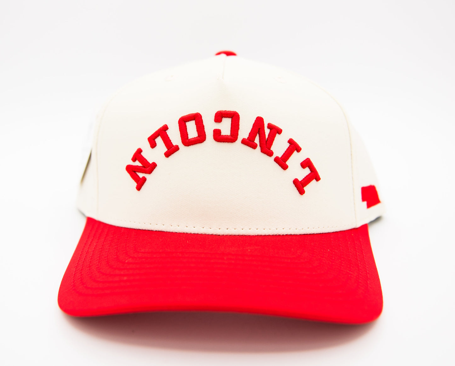 Cream crown and red brim baseball cap with arched 'NEBRASKA' text and side flag