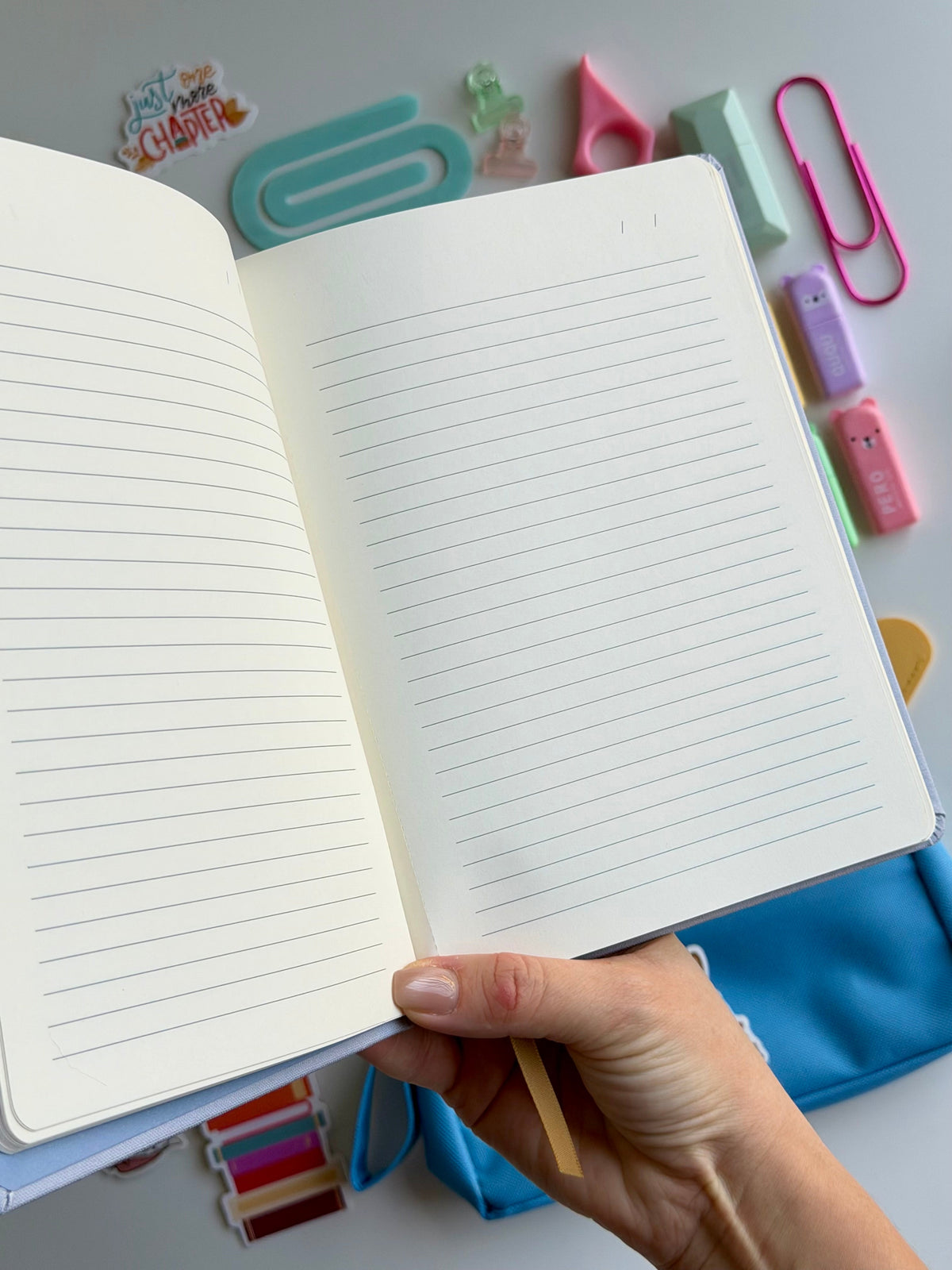 Open dog-themed notebook with lined pages, held in hand, plus blue pencil case