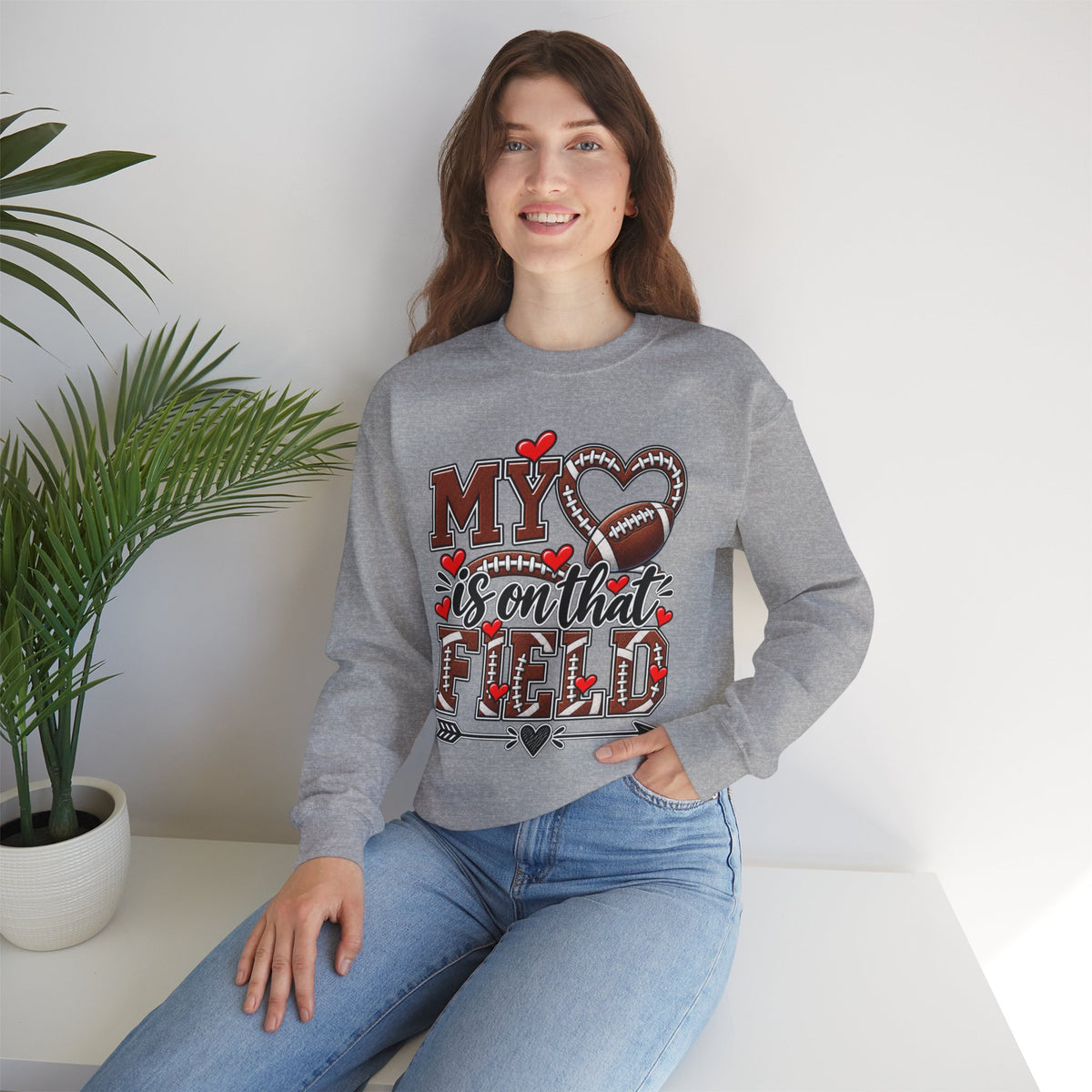 Heather gray crewneck sweatshirt with full football-heart graphic, model standing