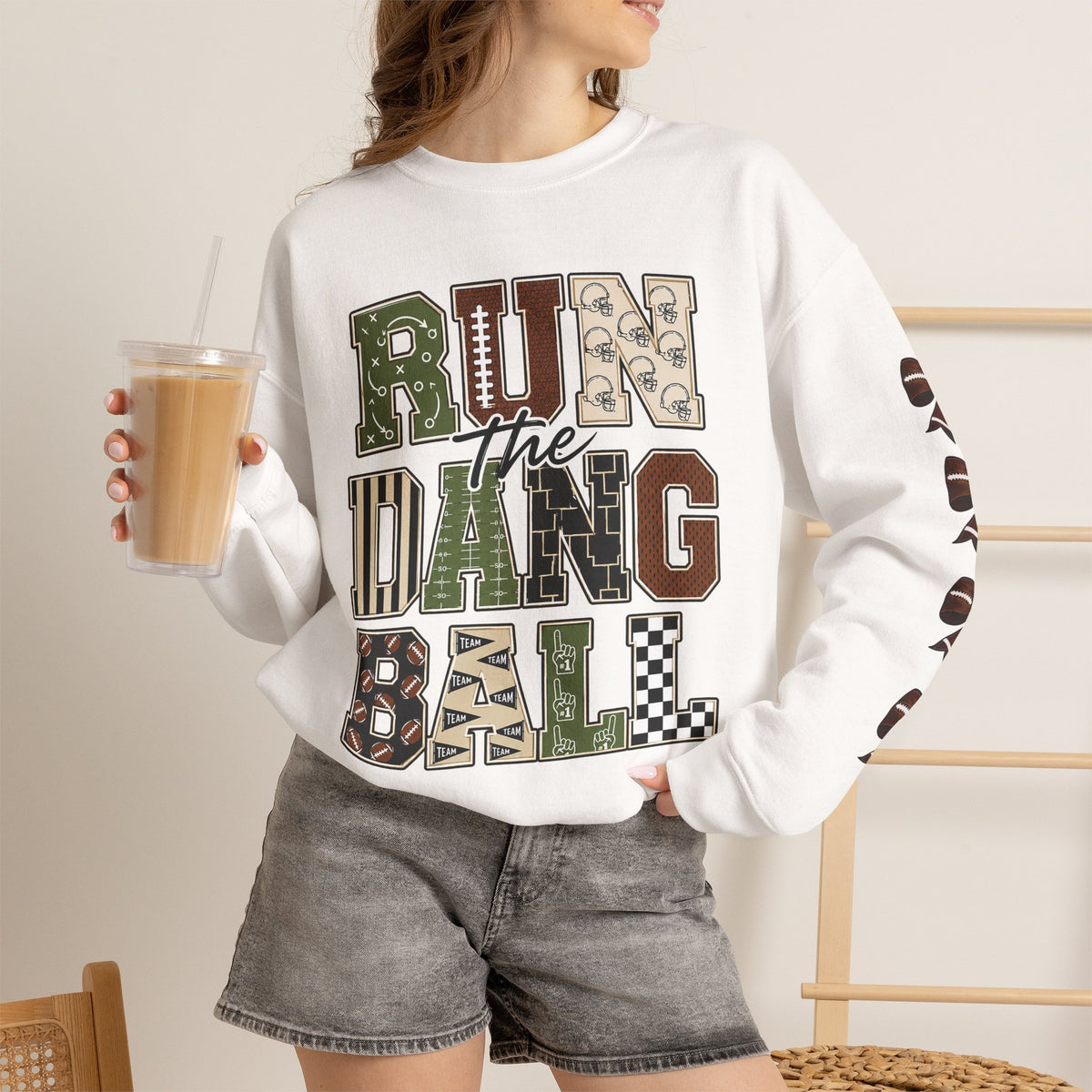 White crewneck sweatshirt on model with retro 'Run the Dang Ball' lettering and ribbon sleeves