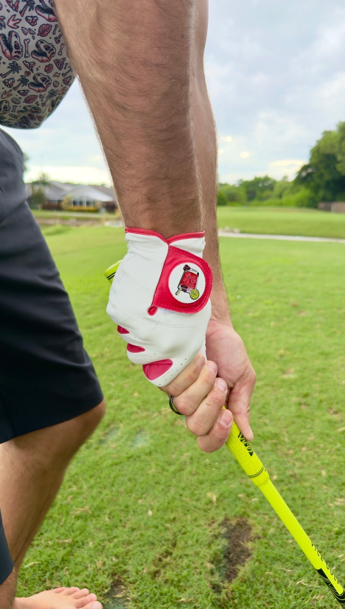 White golf glove with red accents and circular marker pouch, worn on a hand.