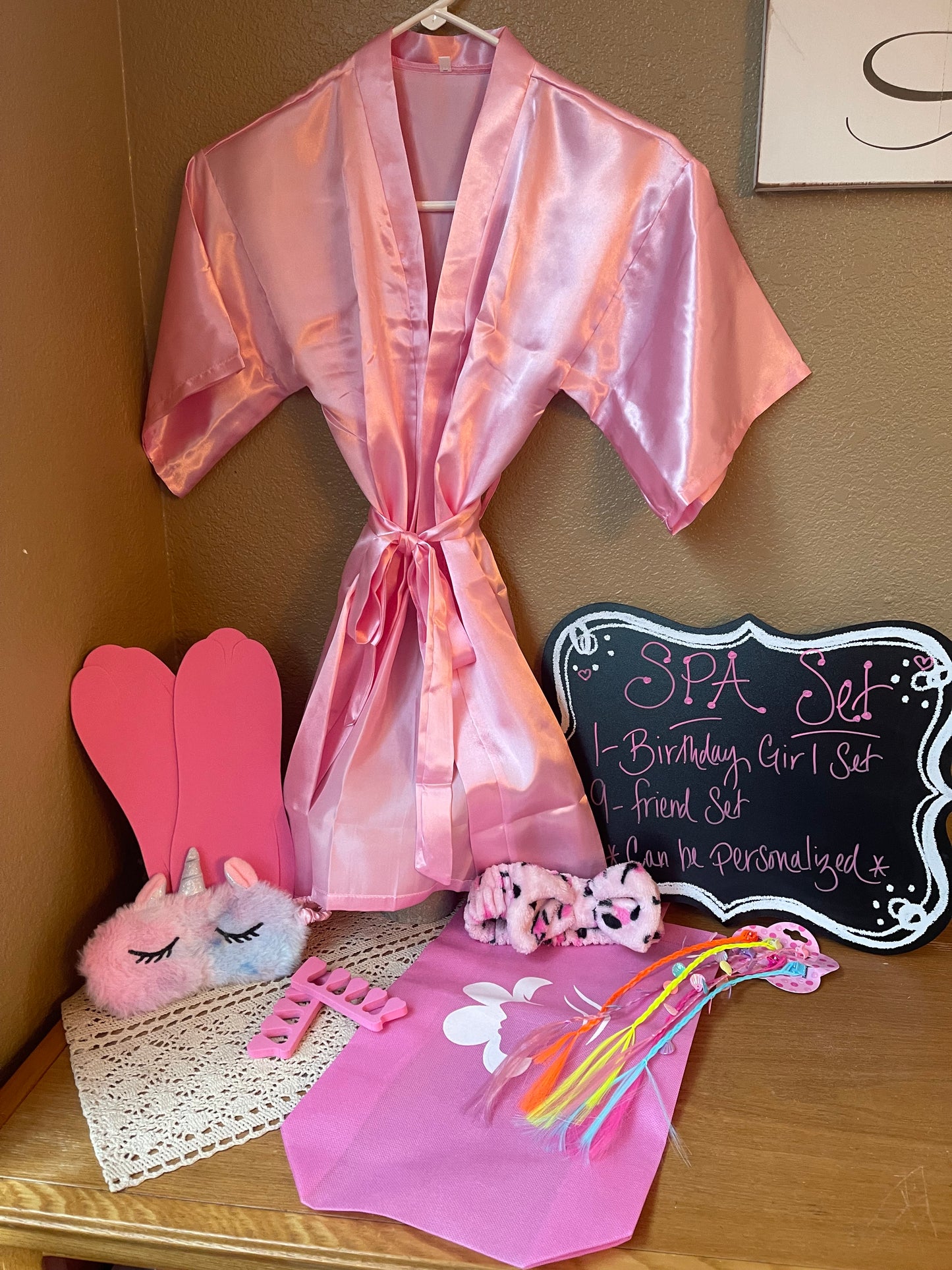 Pink satin spa robe set with tie waist, plush slippers, and bath accessories