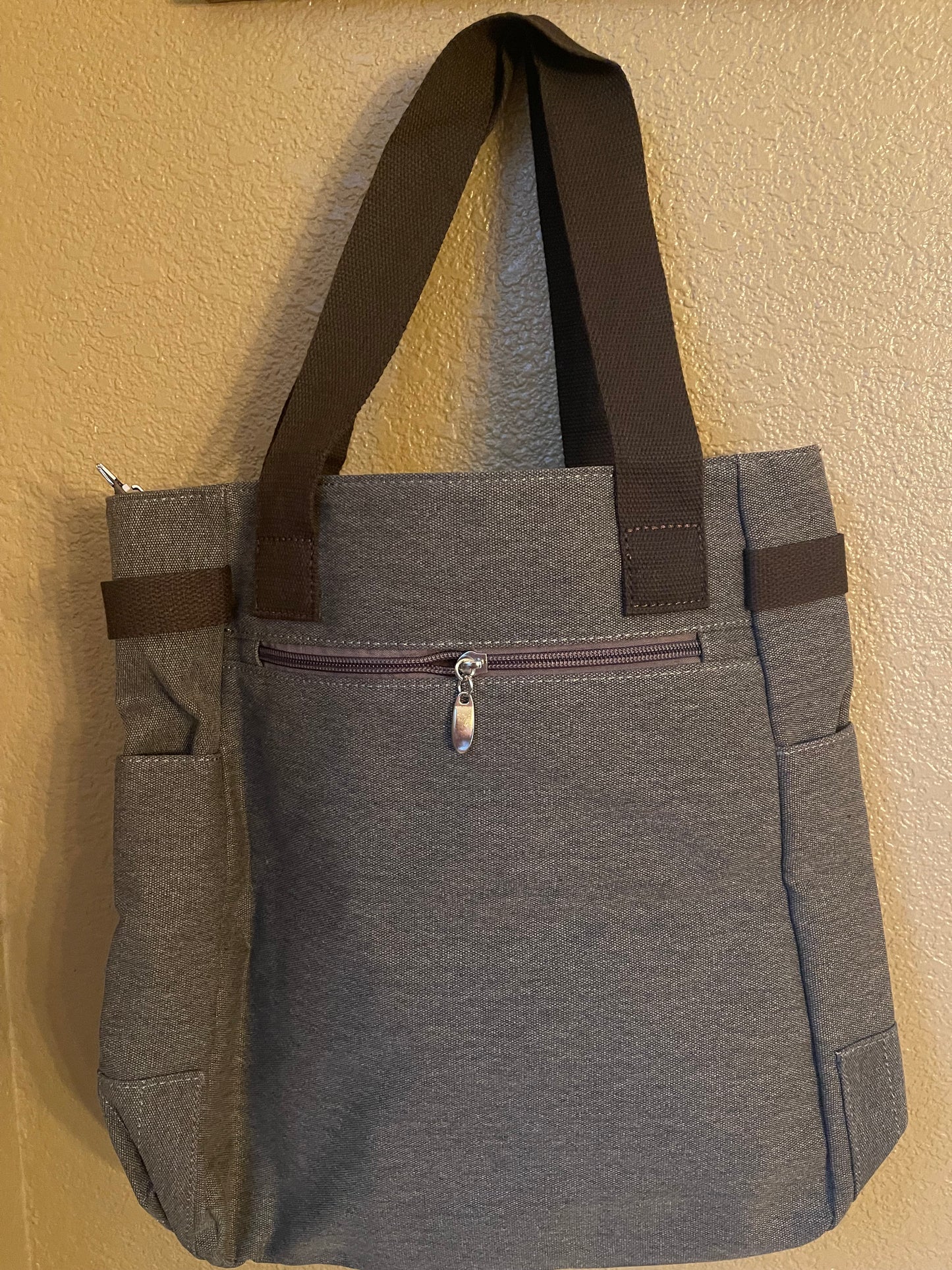 Gray canvas tote bag with front zipper and padded straps