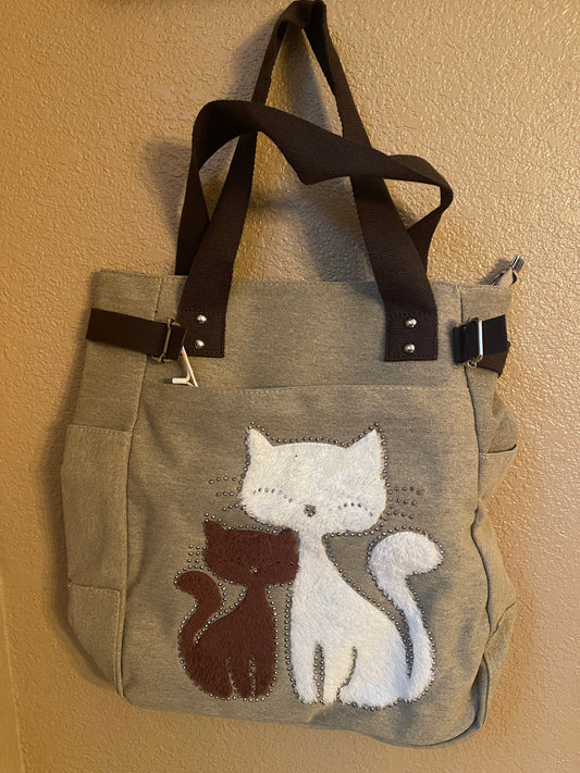 Gray canvas bookbag with embroidered cat graphic, dark handles, snap front pockets