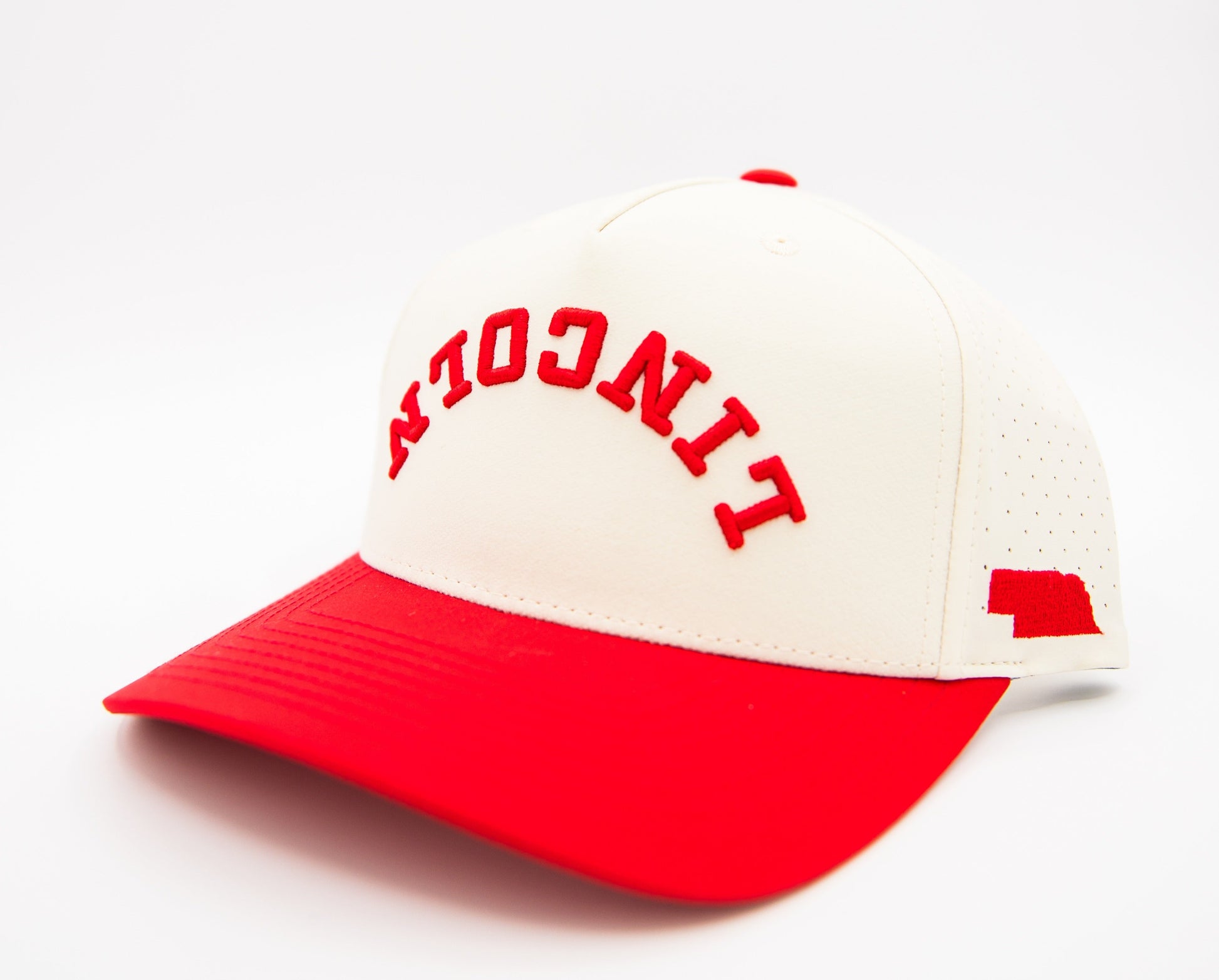 Cream and red baseball cap with arched red 'NEBRASKA' embroidery and side flag logo