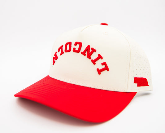 Cream and red baseball cap with arched red 'NEBRASKA' embroidery and side flag logo