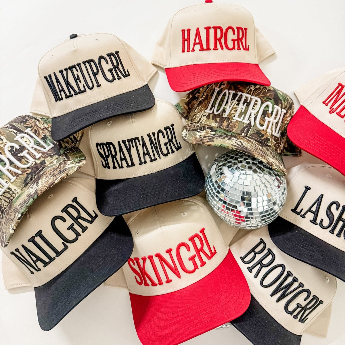 Assorted embroidered trucker hats in cream and black, with one red-and-cream hat