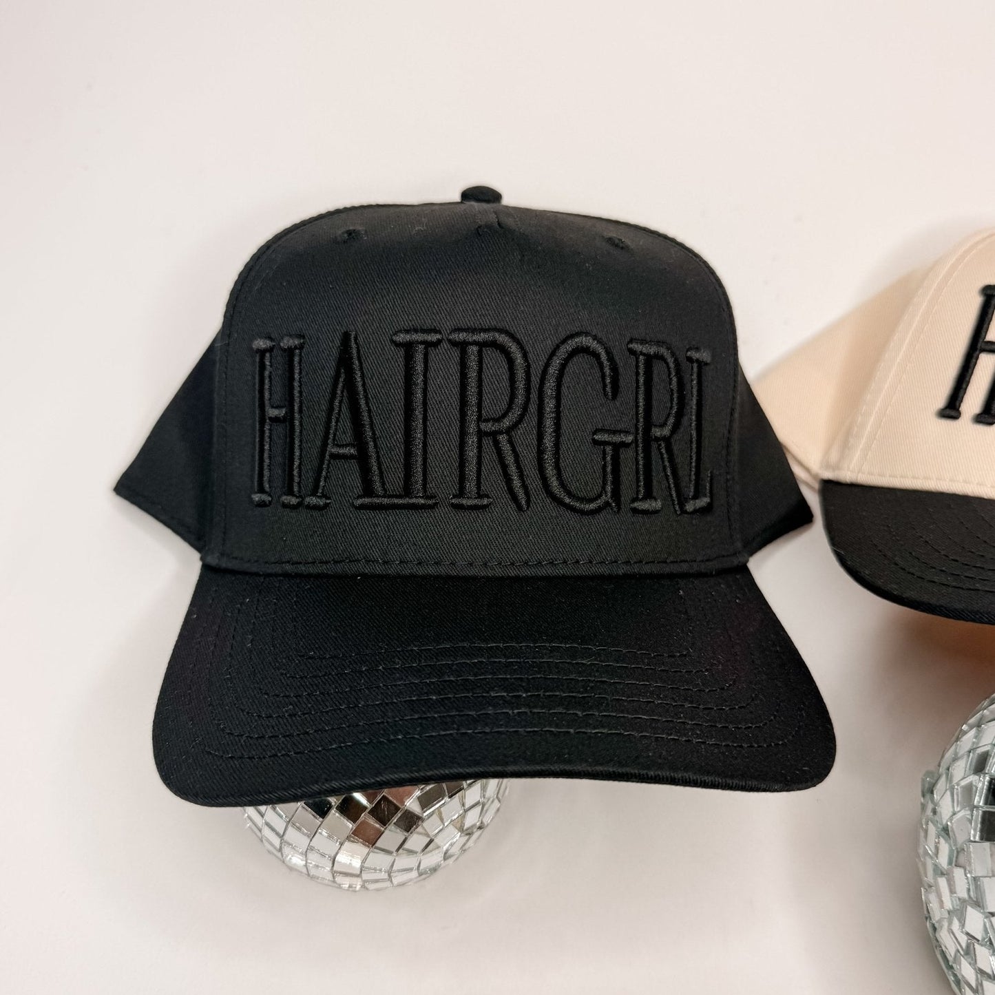 Black HAIRGRL trucker hat with front embroidered logo and curved brim