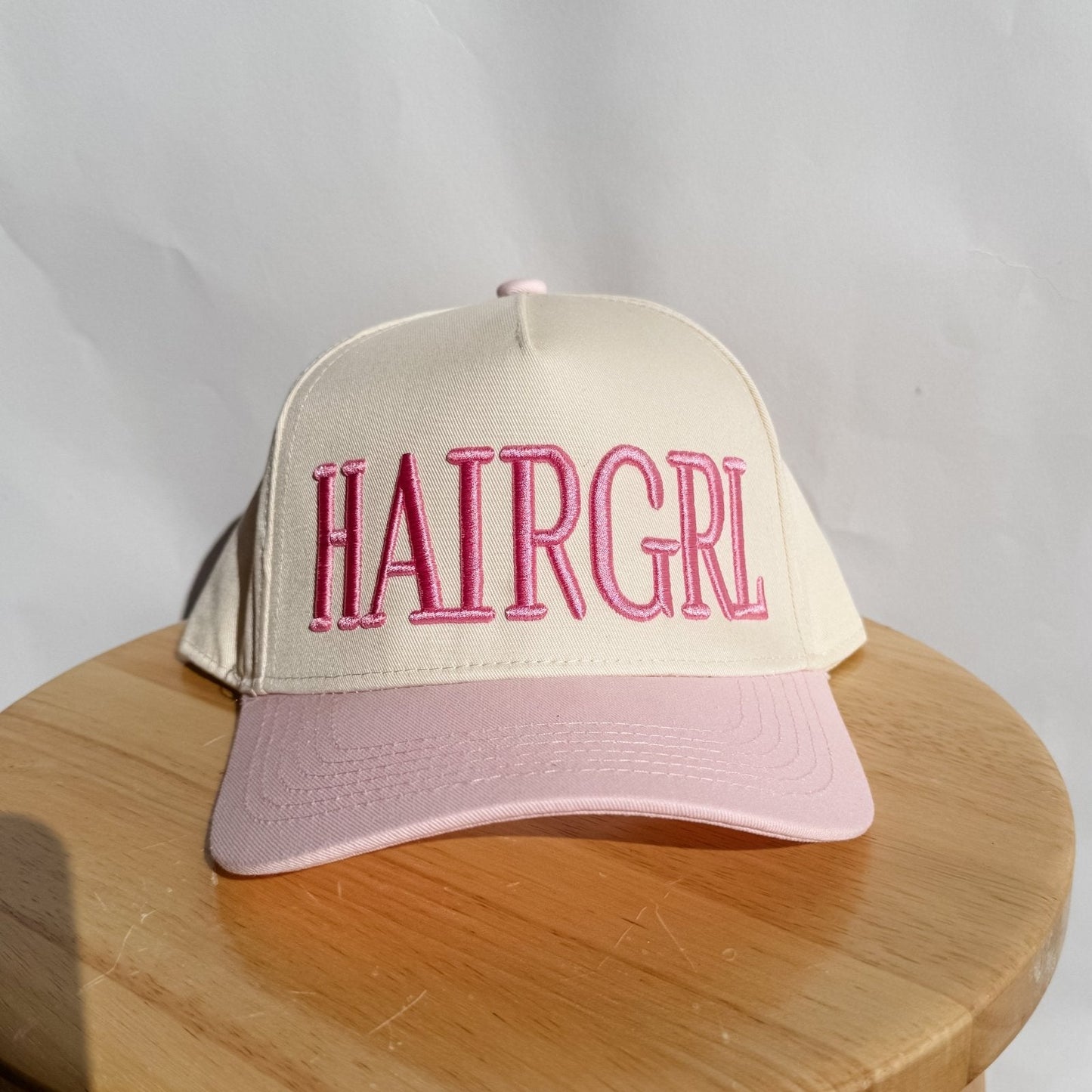 Light cream HAIRGRL trucker hat with pink front logo and light pink brim