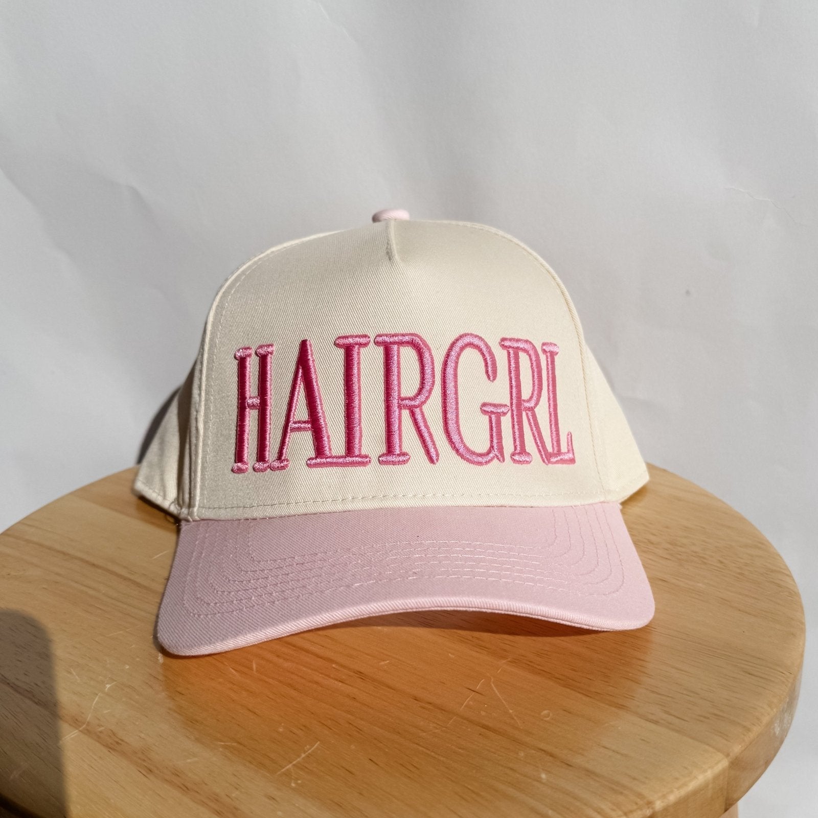 Light cream HAIRGRL trucker hat with pink front logo and light pink brim
