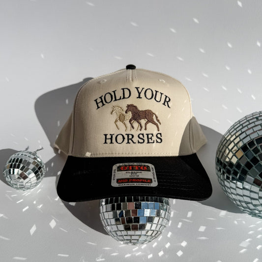 Hold Your Horses trucker hat with beige front, black brim, horse graphic and text logo