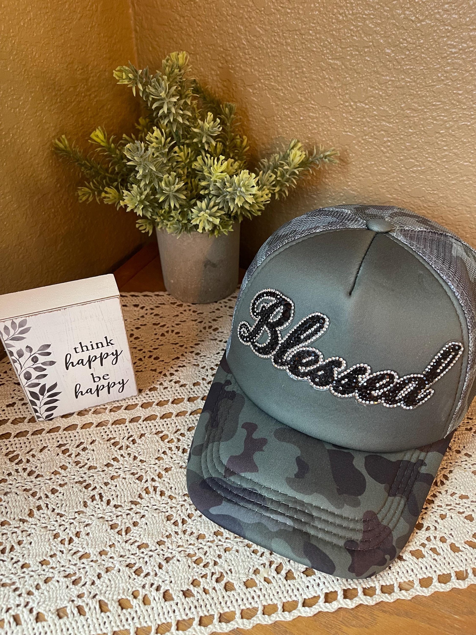 Camo trucker hat with gray front panel and rhinestone “Blessed” script