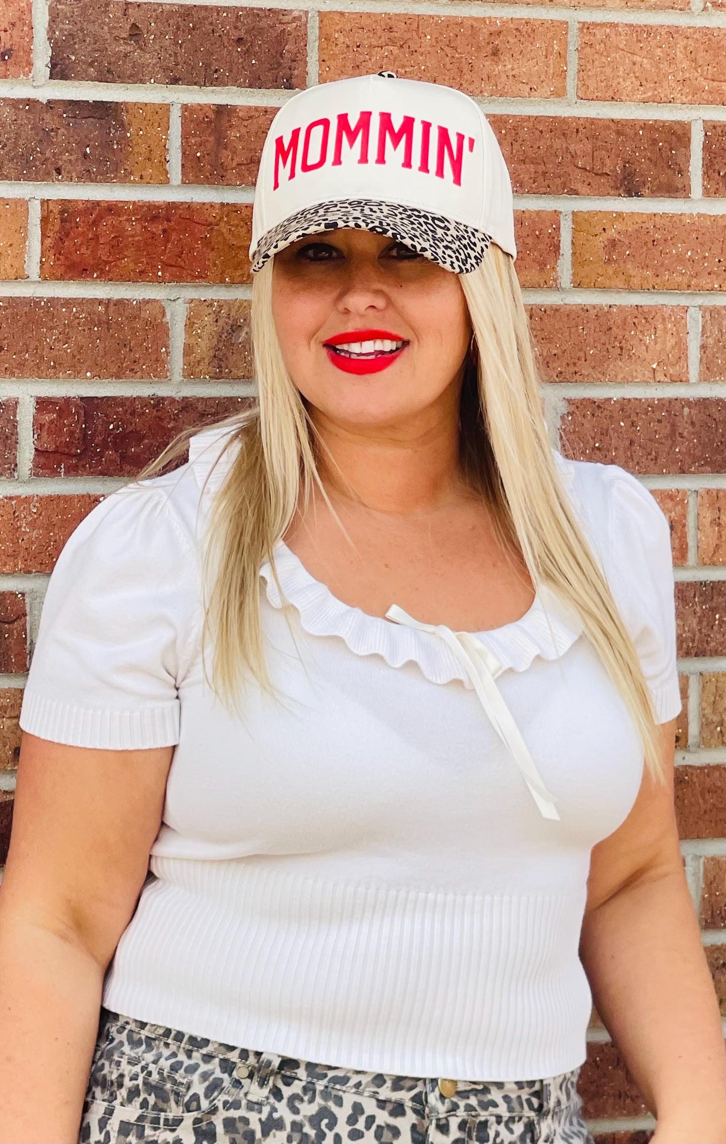 Mommin trucker hat worn by model: cream cap with red MOMMIN and leopard brim