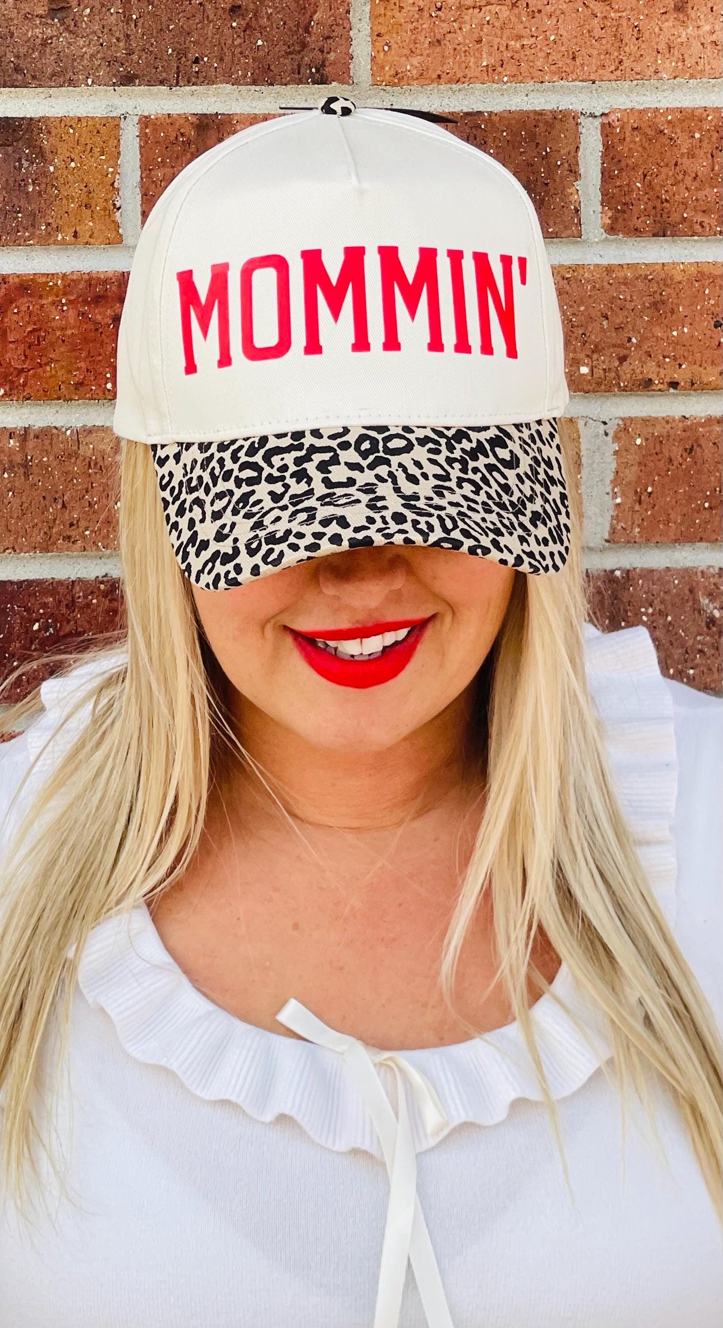 Cream trucker hat with red MOMMIN logo and leopard-print lower panel; model wearing