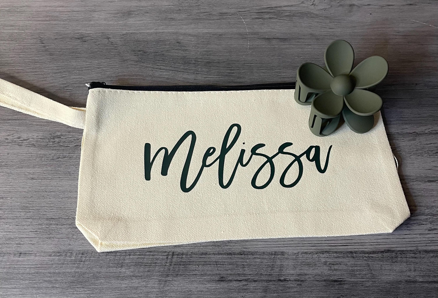 Cream canvas pouch with script 'Melissa' and small flower charm.