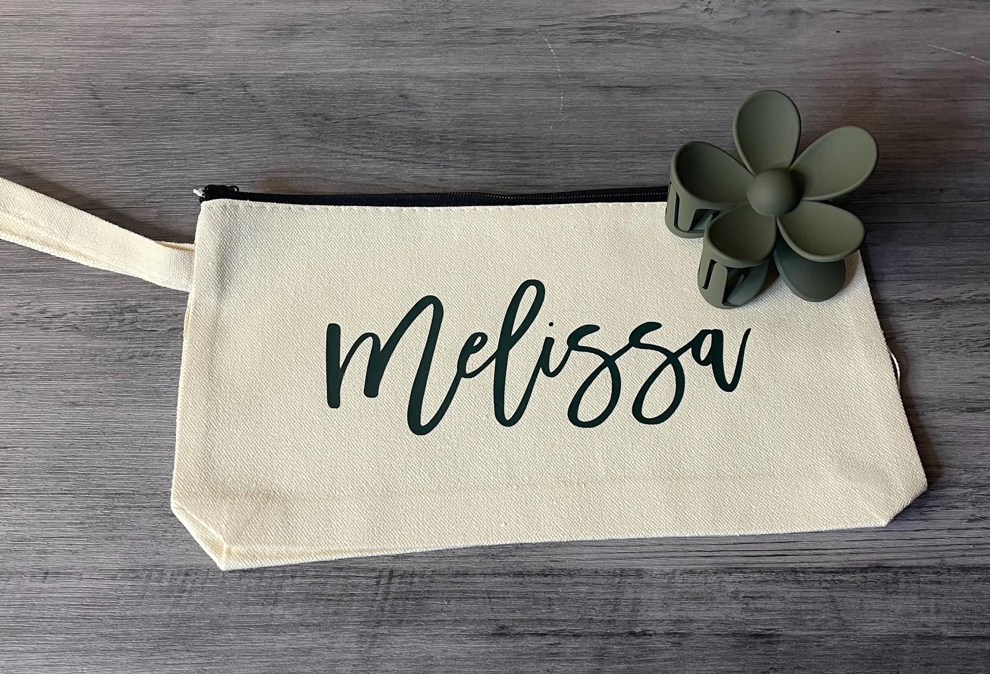 Cream canvas pouch with script 'Melissa' and small flower charm.