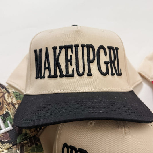 Cream and black trucker hat with bold black embroidered-style lettering on front