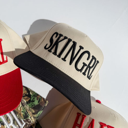 Cream trucker hat with black brim and SKINGRL front logo